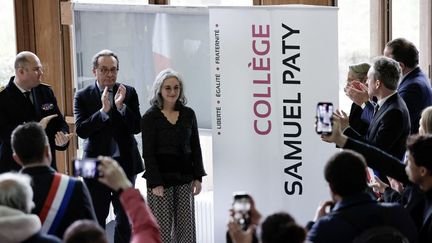 Le président du conseil départemental des Yvelines, Pierre Bedier, et la sœur de Samuel Paty, Gaëlle, se tiennent à gauche d'une plaque qui donne au collège le nom de l'enseignant assassiné, à Conflans-Sainte-Honorine (Yvelines), le 14 mars 2025. (STEPHANE DE SAKUTIN / AFP)