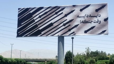 Un panneau publicitaire sur lequel est inscrit le message "C'est la guerre !", à Téhéran (Iran), le 22 juin 2025. (ATTA KENARE / AFP)