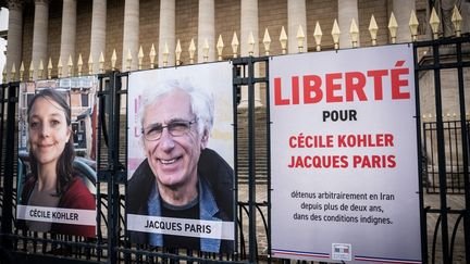 Des affiches sur les grilles du siège de l'Assemblée nationale pour demander la libération des deux otages français retenus en Iran, Cécile Kohler et Jacques Paris, le 26 mars 2025. (XOSE BOUZAS / HANS LUCAS / AFP)