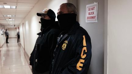 Des agents de la police anti-immigration américaine dans le couloir d'un tribunal new-yorkais, le 17 mars 2026. (CHARLY TRIBALLEAU / AFP)